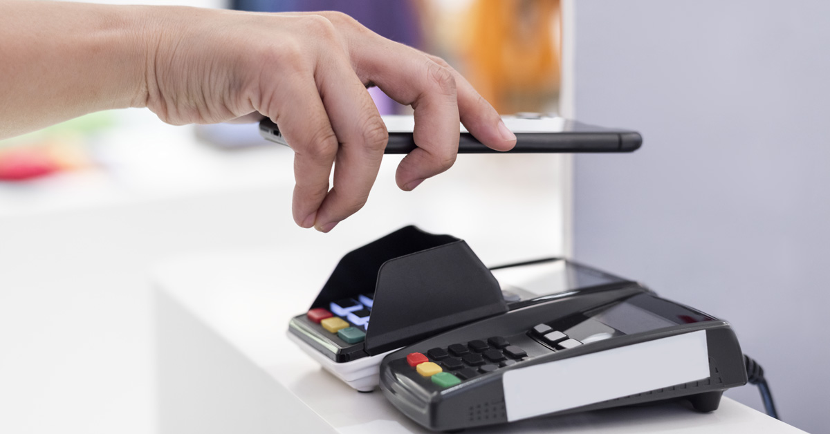 Someone uses their mobile phone to make a payment, one of the top payment processing trends of 2023.