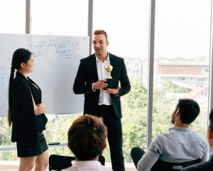 A manager presents an award and recognizes an employee for exemplary performance during a meeting.